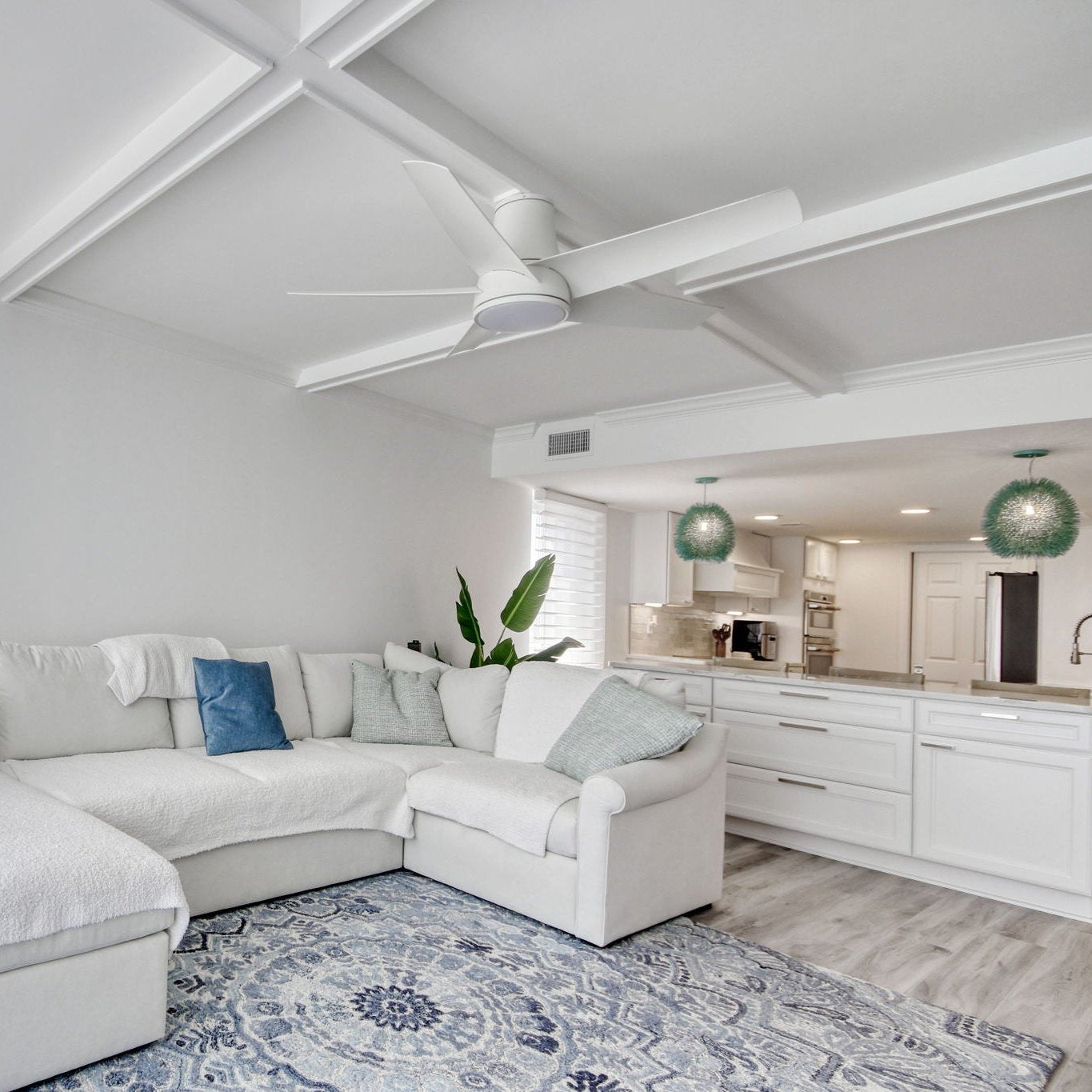 a living room scene with a white couch with blue pillows