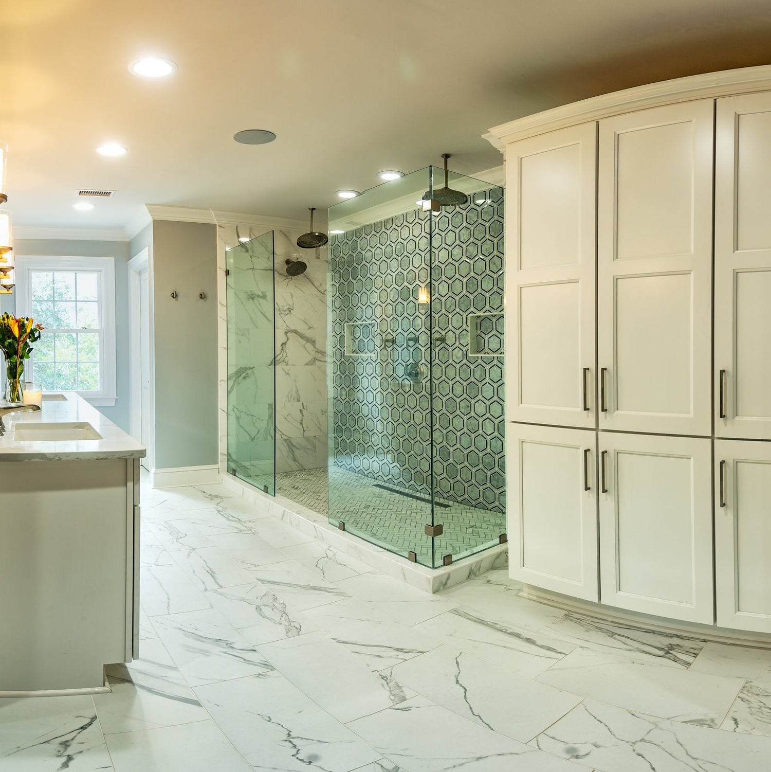 A bathroom scene with a double walk in shower with marble flooring