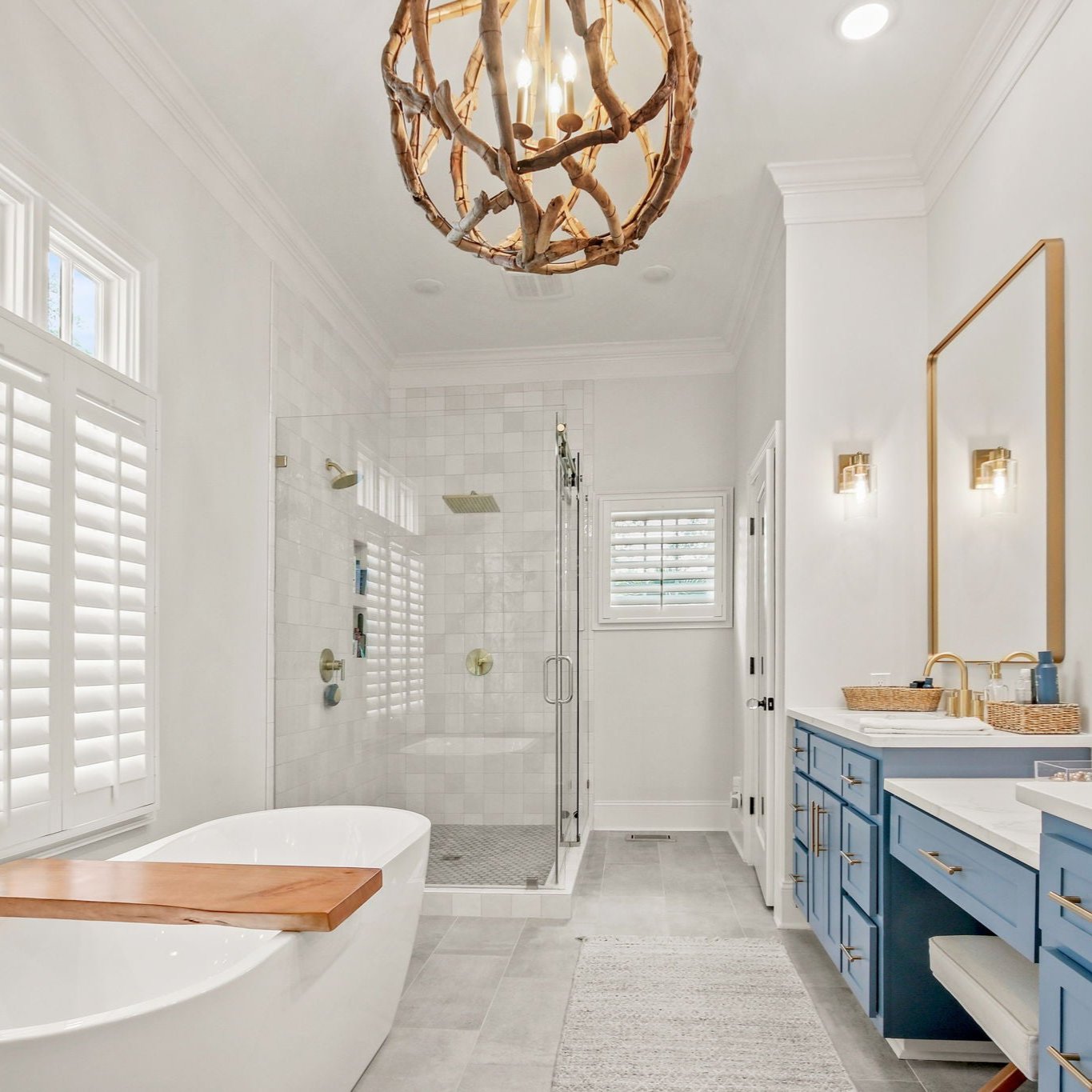 bathroom scene with blue cabinets and a tile shower with a floating tub with gold accents