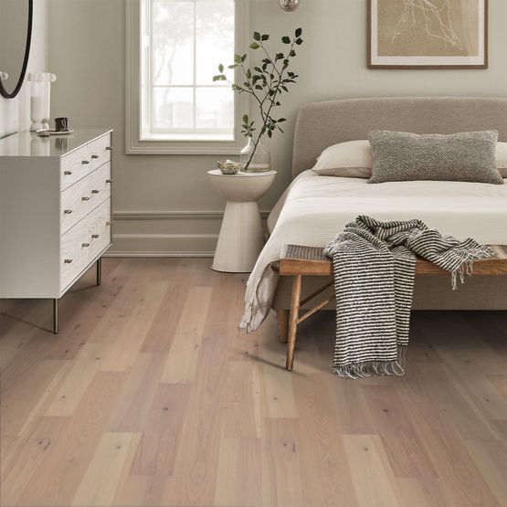 This is a room scene of the floor imperial pecan in the color barley. This is a bedroom with a cream bed frame with white sheets and white furniture.
