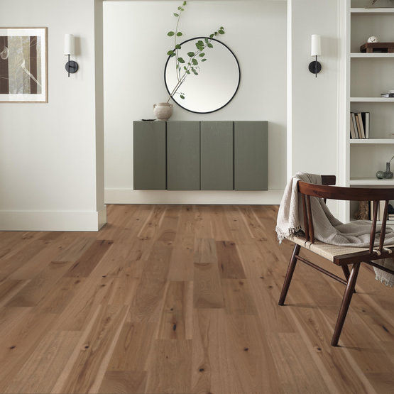 This is a room scene of imperial pecan hardwood flooring. it is an entry way with a circle mirror and green floating shelves