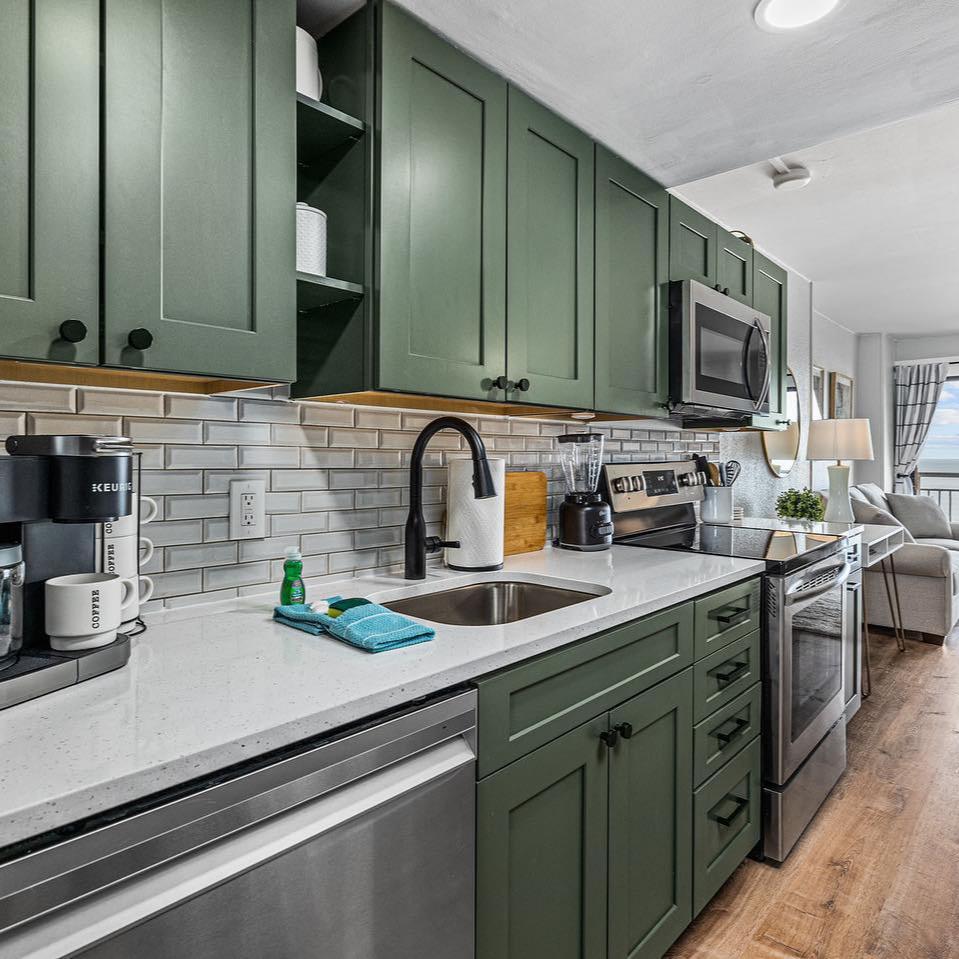 a kitchen with green cabinets and black hardware