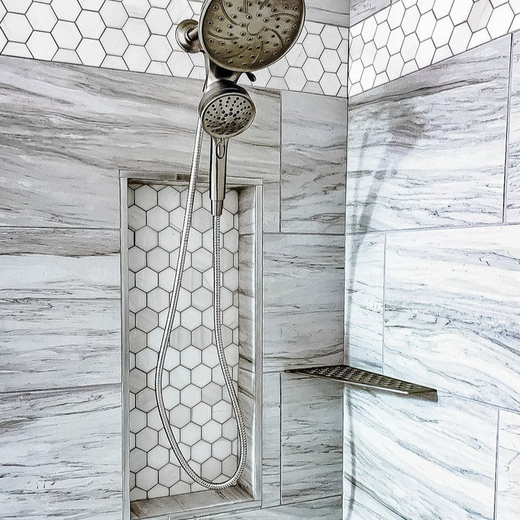 Shower setup with handheld showerhead and wall-mounted showerhead in a tiled shower area.