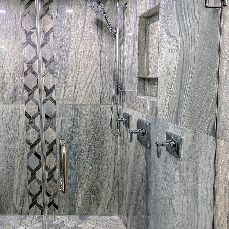 Modern shower with gray tiled walls and a geometric patterned tile.