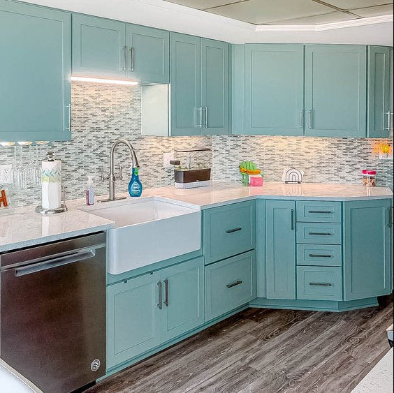 Modern kitchen with teal cabinets, white sink, and stainless steel dishwasher.