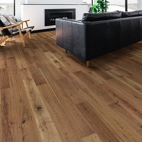 This is a room scene of imperial pecan in wheat with a black leather couch and a white and black fireplace