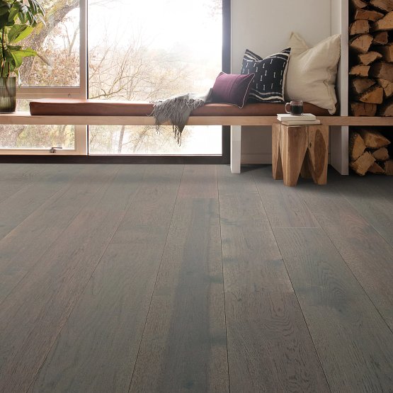 This is a room scene of the imperial pecan flooring in an open sun room with a small bench seating under the window with pillows