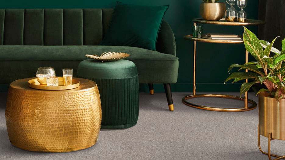 This is a living room scene with a emerald green couch accented with gold furniture