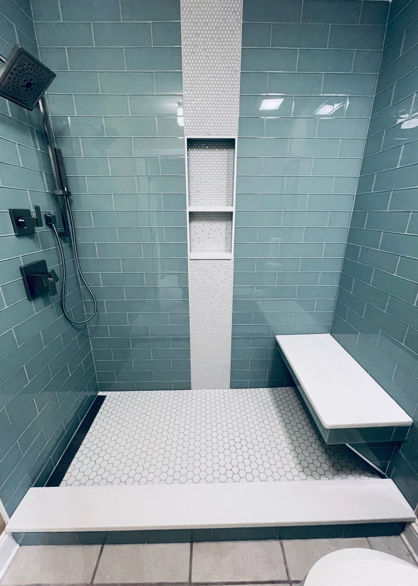 A blue tile shower install with a penny round waterfall.