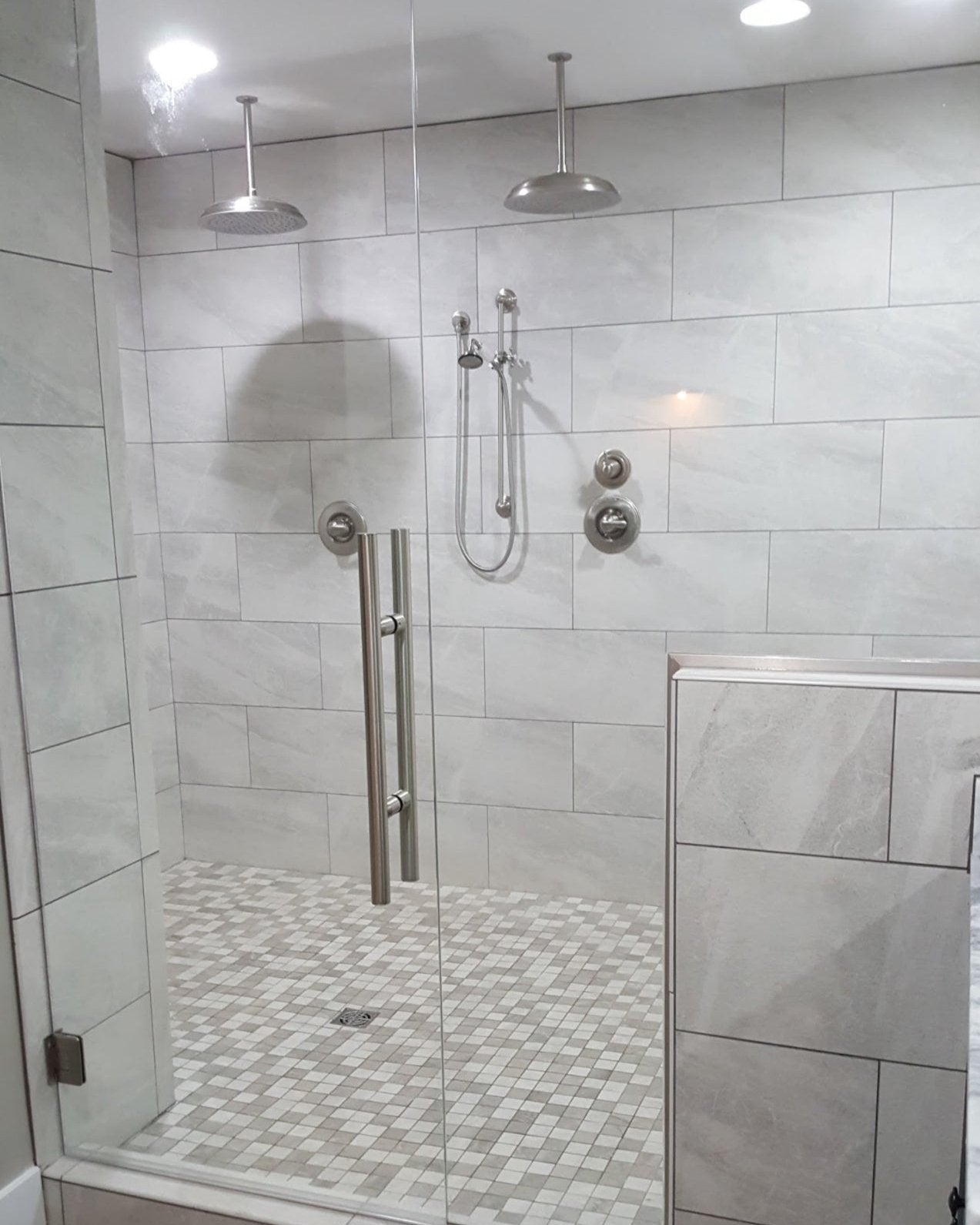 a walk in shower with two shower heads and a grey tile