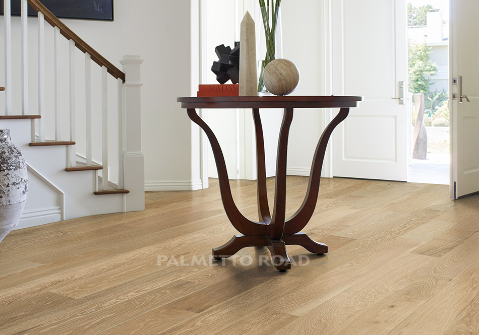 This is a room scene of an entry way with a dark wooden table front and center with decor pieces on top. The hardwood flooring is monet in the color clermont