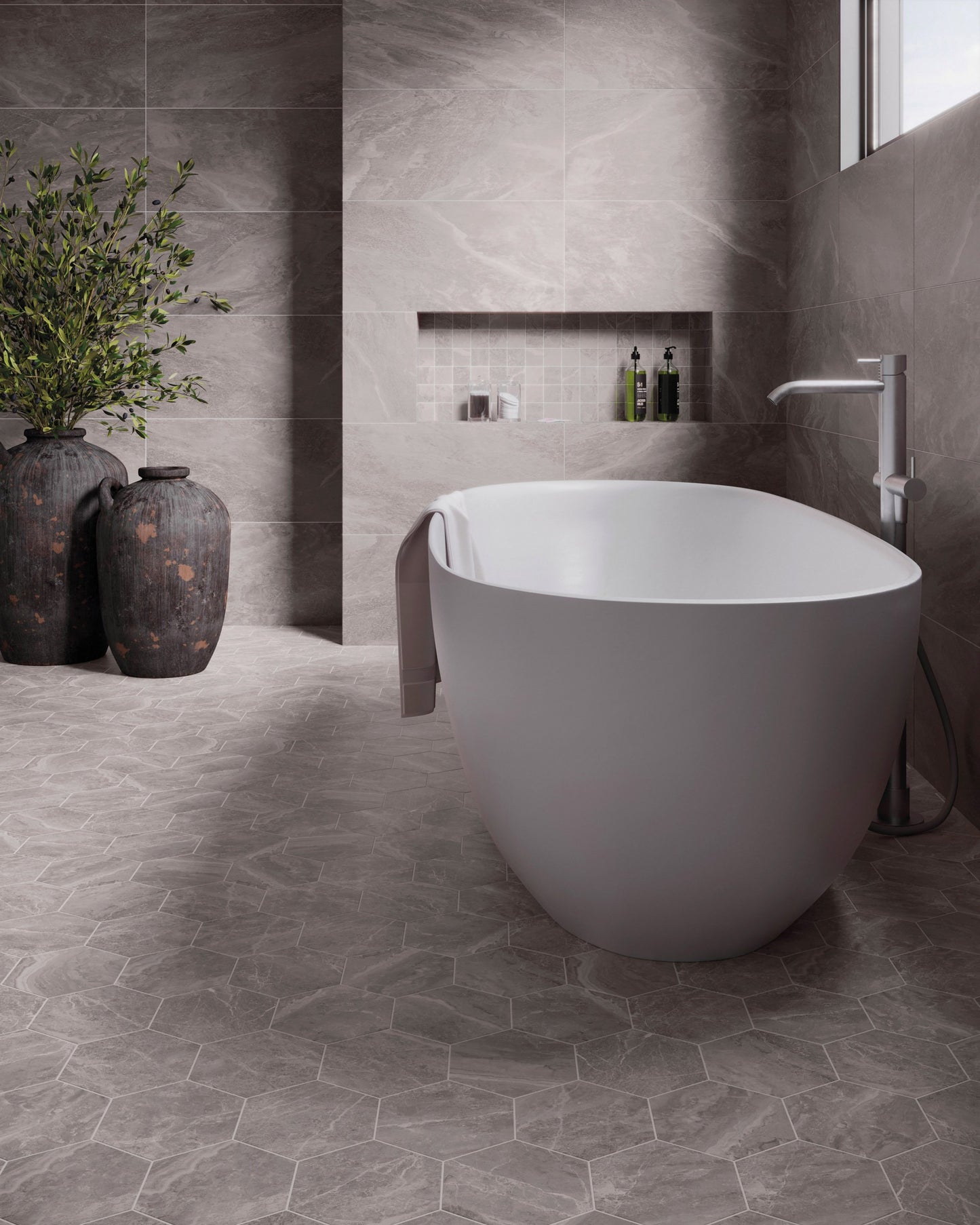 This is a room scene of a bathroom with a white tub and potted plants. The tile used is storm in the color grey.