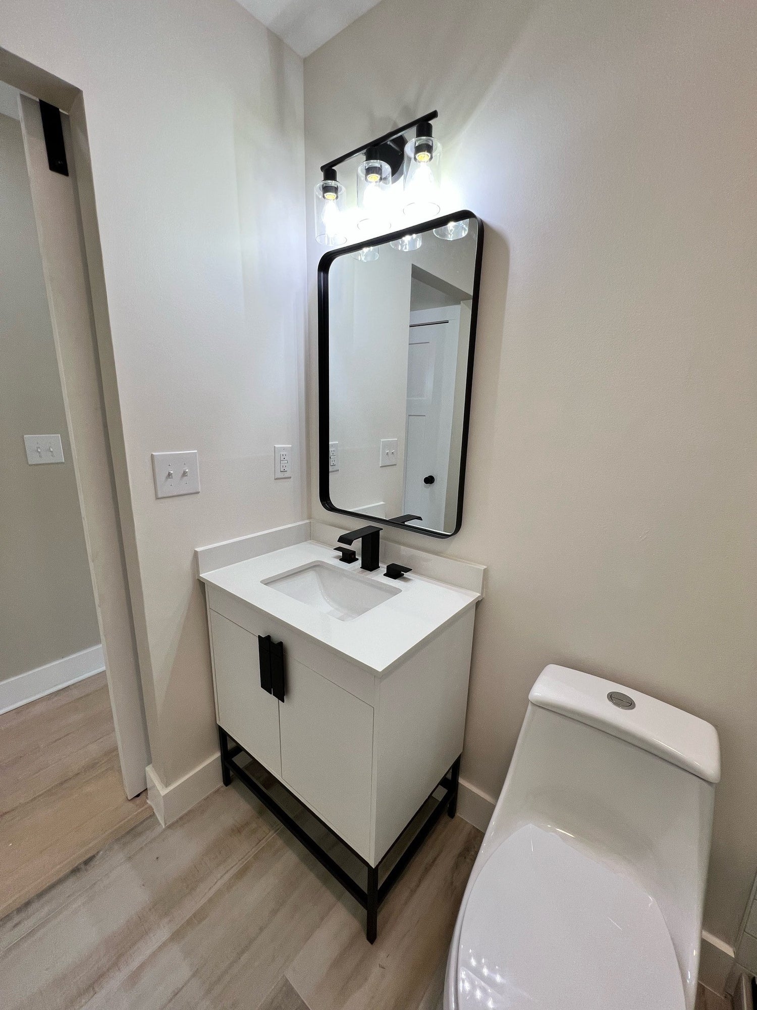 a bathroom sink with a black rectangle mirror
