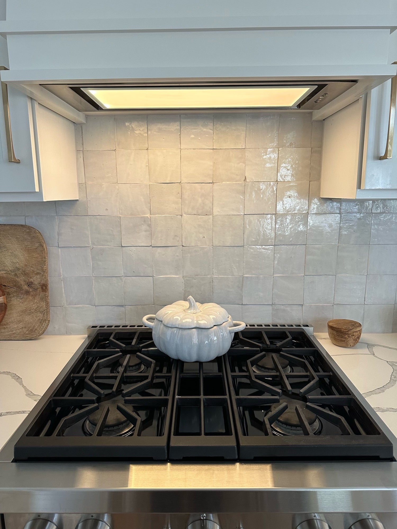 A kitchen backsplash with a pumpkin ceramic bowl on top of the stove
