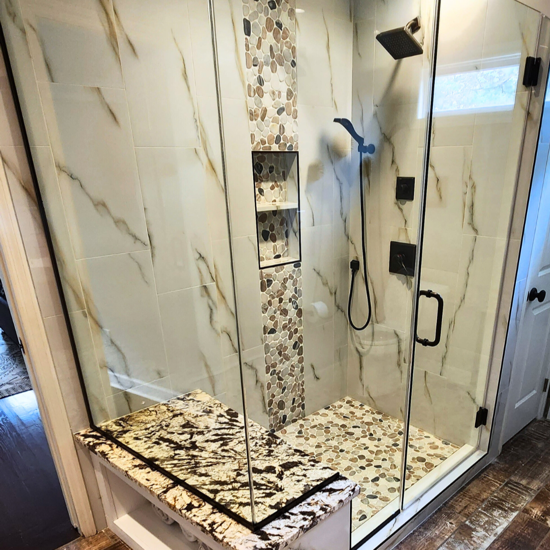 Modern shower with glass enclosure and marble-patterned tiles on a wooden floor.