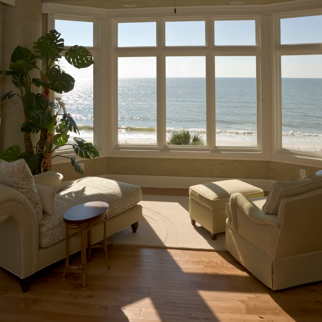 living room facing the ocean with vinyl plank flooring and cream colored furniture