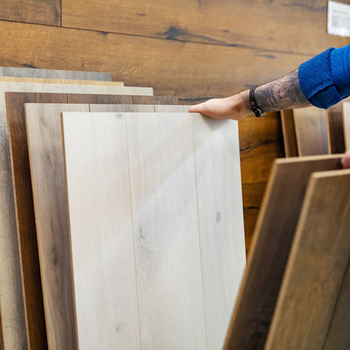 A man with tattoos looking through flooring samples