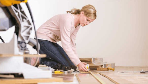 woman measuring room for vinyl plank flooring