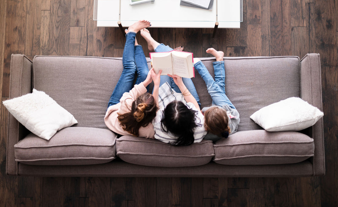 A family reading together in their room with dark hardwood flooring