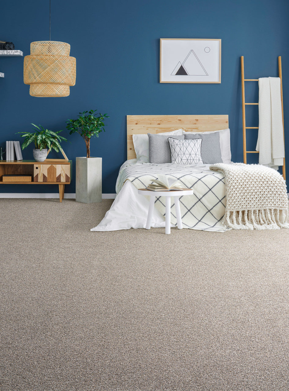 gold standard carpet in a bedroom setting. The room has blue walls with a natural wood blanket ladder with a cream blanket draped over.