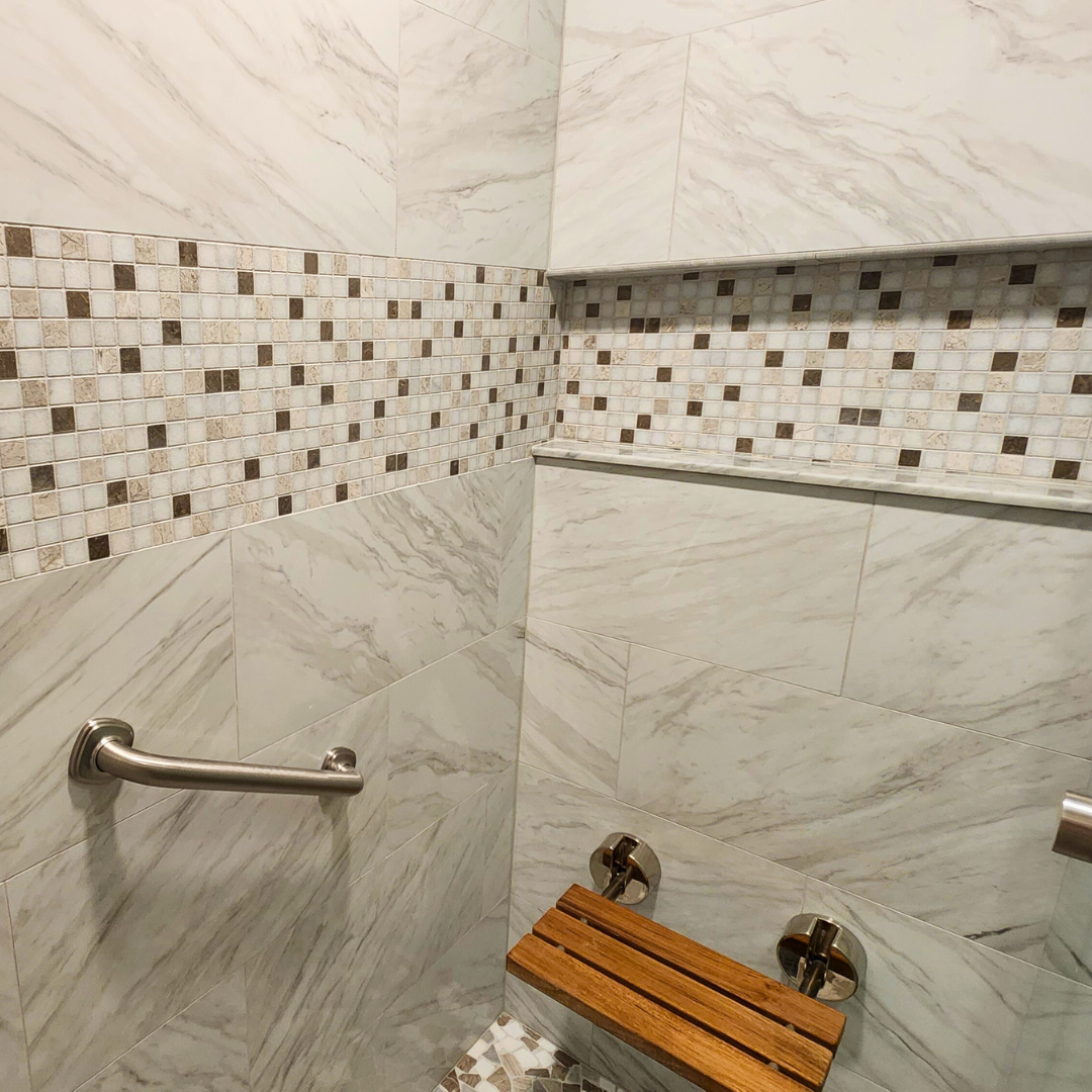 Shower with tiled walls, grab bar, and wooden bench.