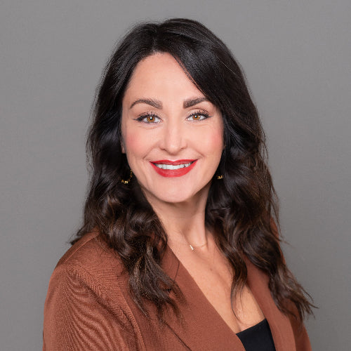 Woman wearing a brown blazer against a gray background