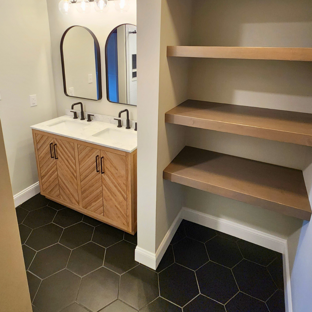 Bathroom with wooden vanity, mirror, and shelves.
