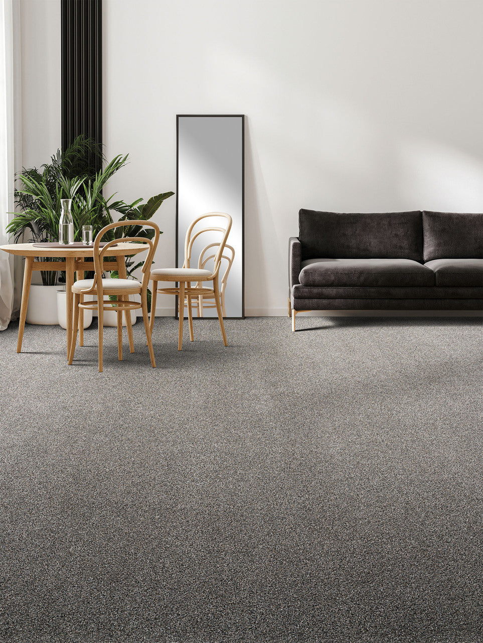 gold standard carpet in a living room setting with a grey couch. There is a natural wood dining room table with water on top.