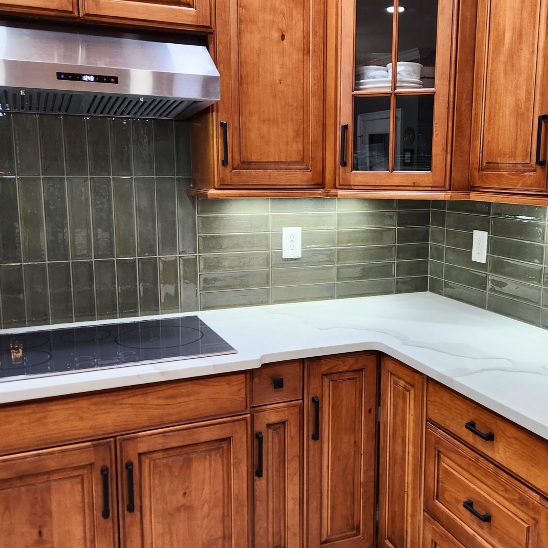 Kitchen with wooden cabinets, stainless steel range hood, and green tiled backsplash.