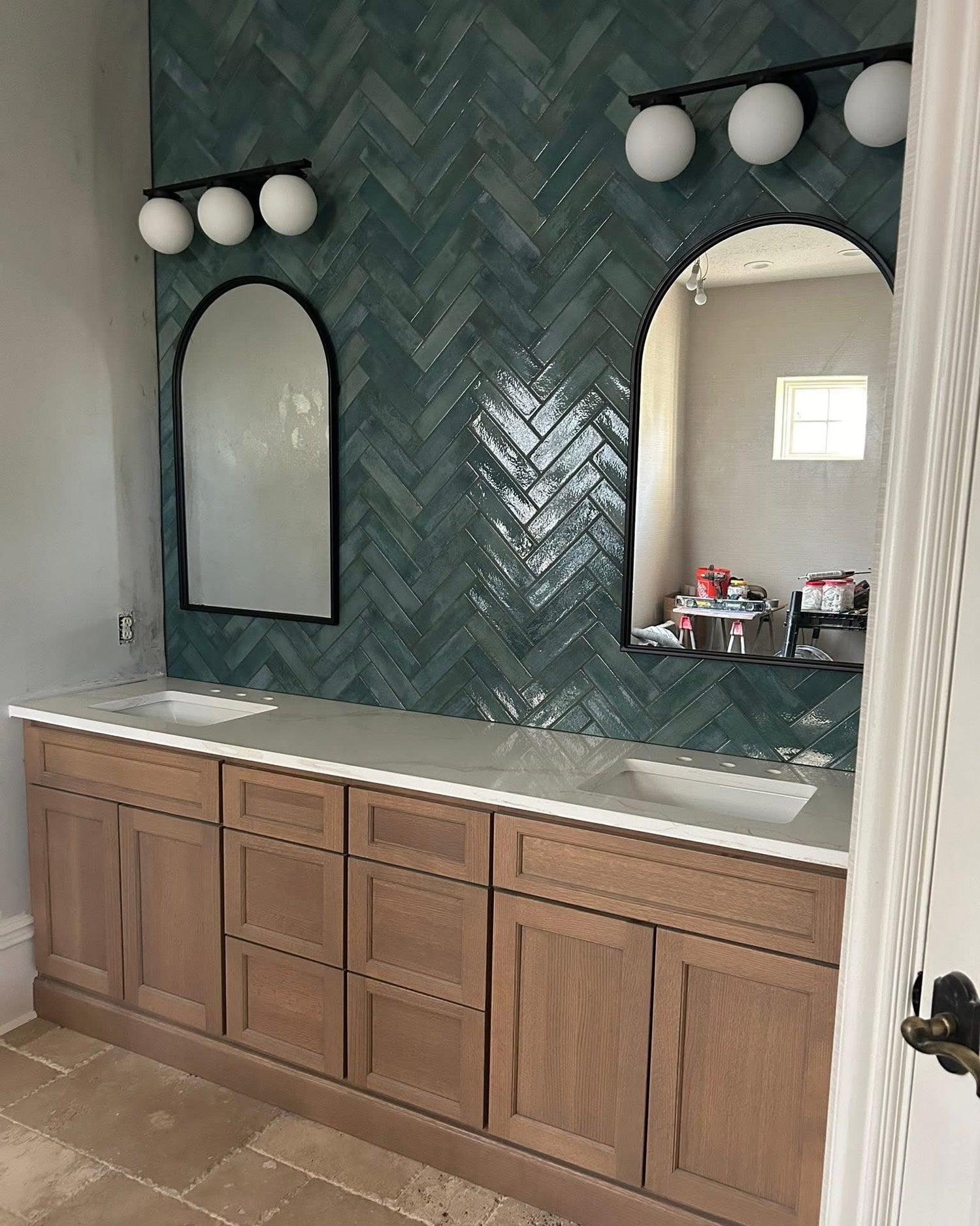Bathroom vanity with wooden cabinets, white countertop, and green tiled wall.