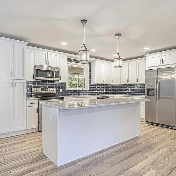 Modern kitchen with white cabinets, stainless steel appliances, and a island.
