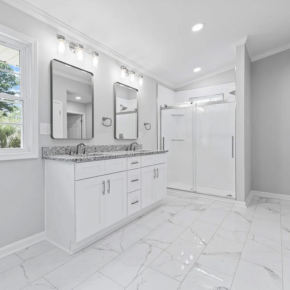 Modern bathroom with white vanity, mirror, and shower stall.