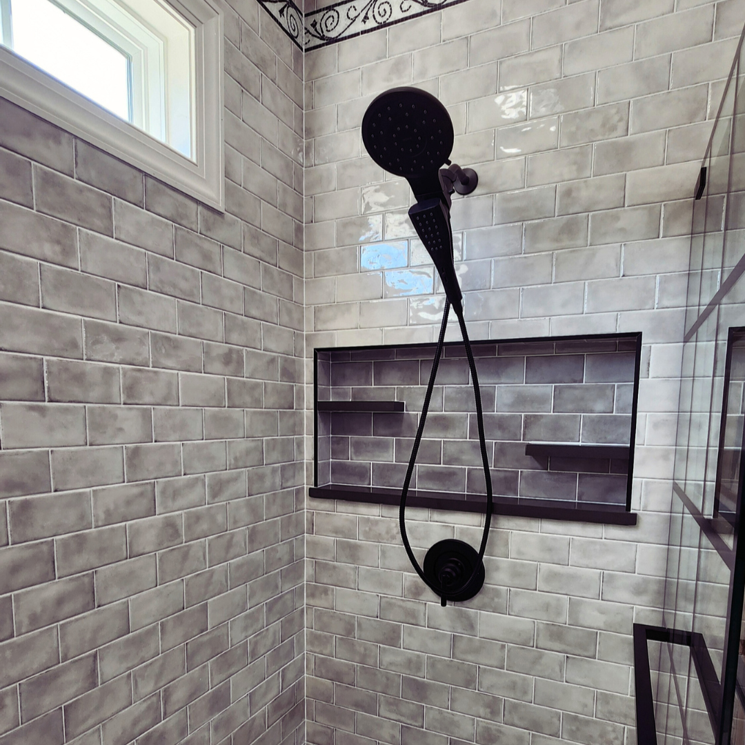 Shower area with tiled walls and a handheld shower head.