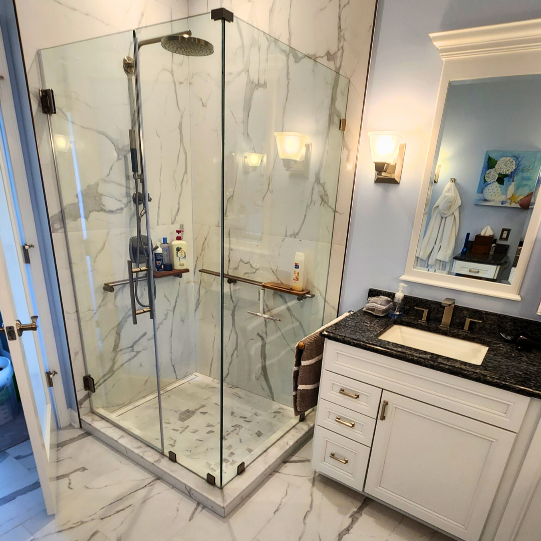Modern bathroom with glass shower enclosure, marble floor, and vanity.