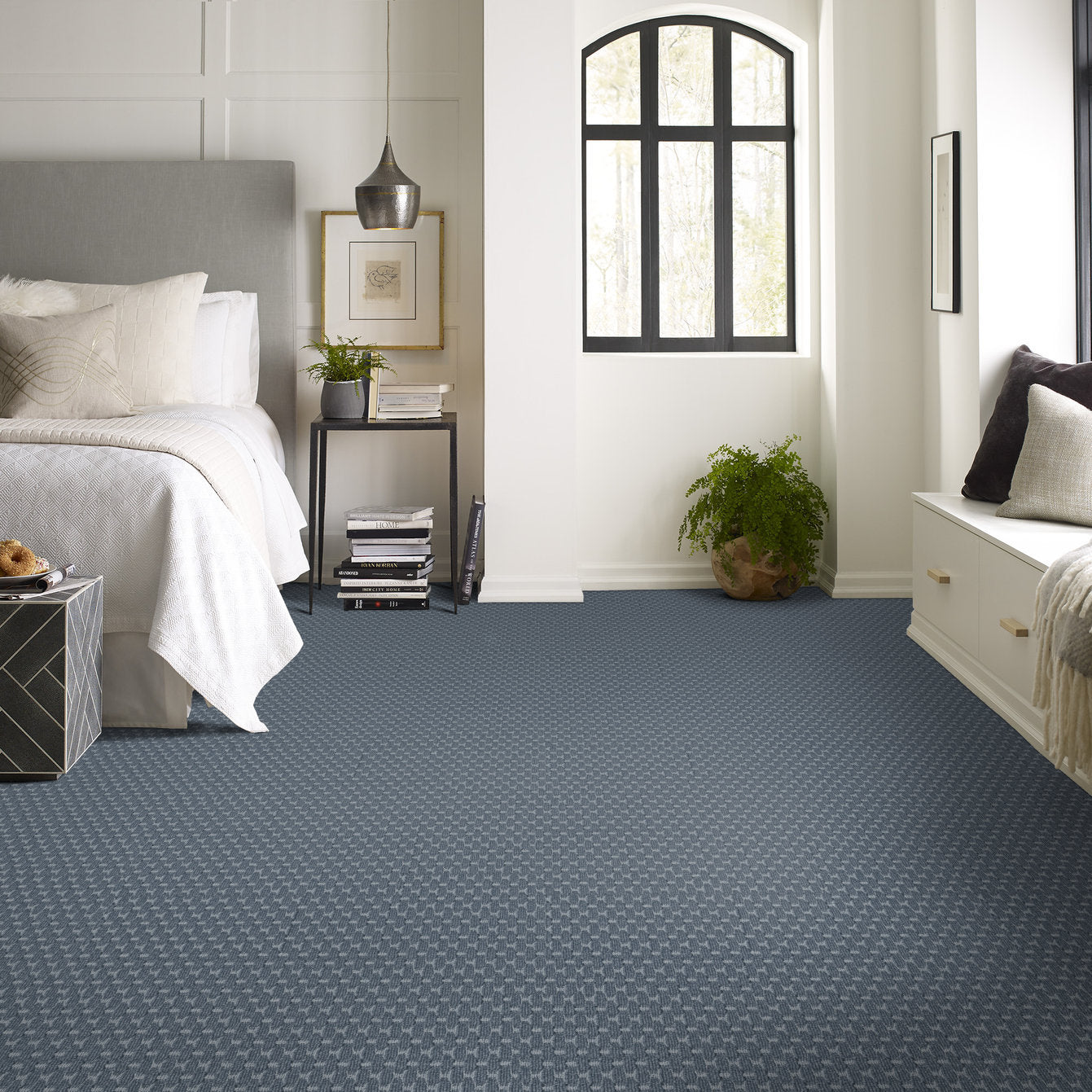 a bedroom display with blue pattern carpet and a white bed spread