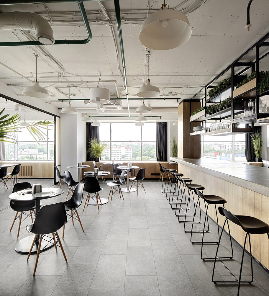 This is a room scene of a restaurant with the tile flooring being westmont quarry. There are black barstools and greenery everywhere 